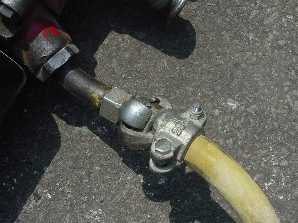 Claw-type coupling joining a yellow compressed-air hose to a jackhammer fitting