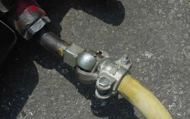 Claw-type coupling joining a yellow compressed-air hose to a jackhammer fitting