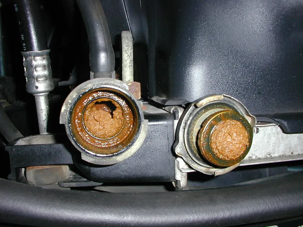 Radiator inlet and outlet necks caked with rust-colored sludge from neglected coolant
