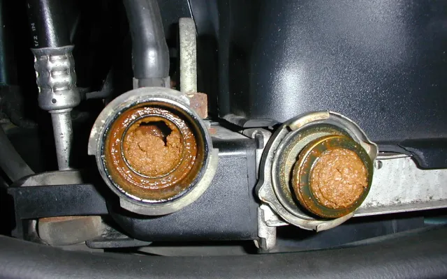 Radiator inlet and outlet necks caked with rust-colored sludge from neglected coolant