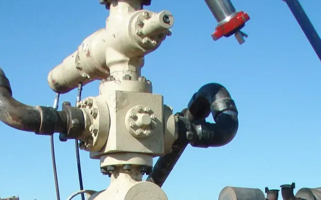 Frac head on a wellhead with treating iron and hammer union connections, red wing nut on a suspended line