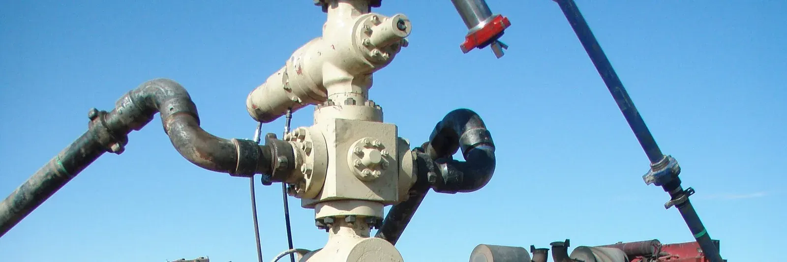 Frac head on a wellhead with treating iron and hammer union connections, red wing nut on a suspended line