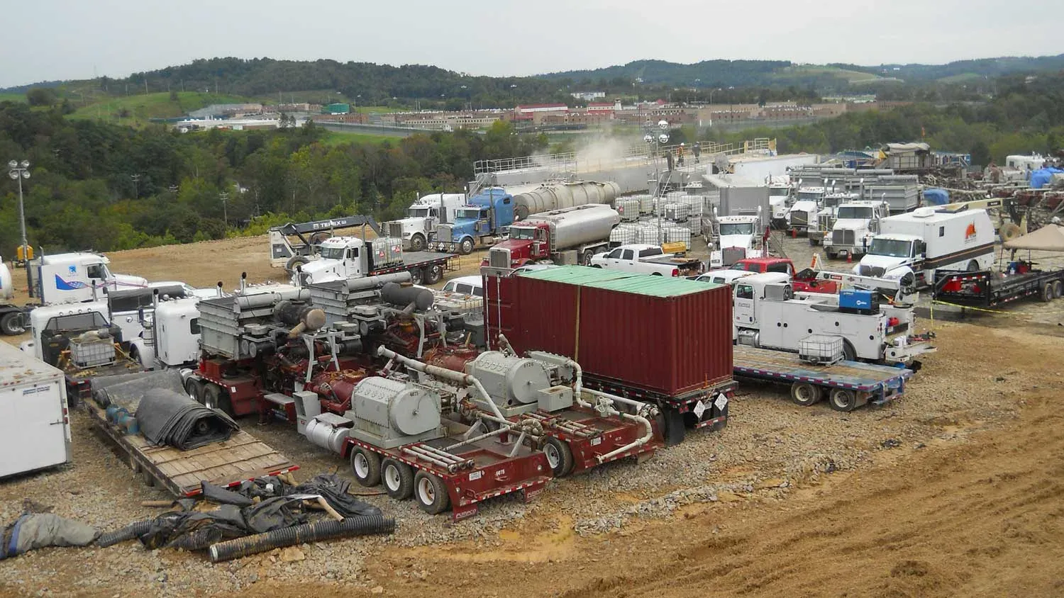 Hydraulic fracturing well site with pump trucks, frac iron, tanks and support trucks spread across a gravel pad