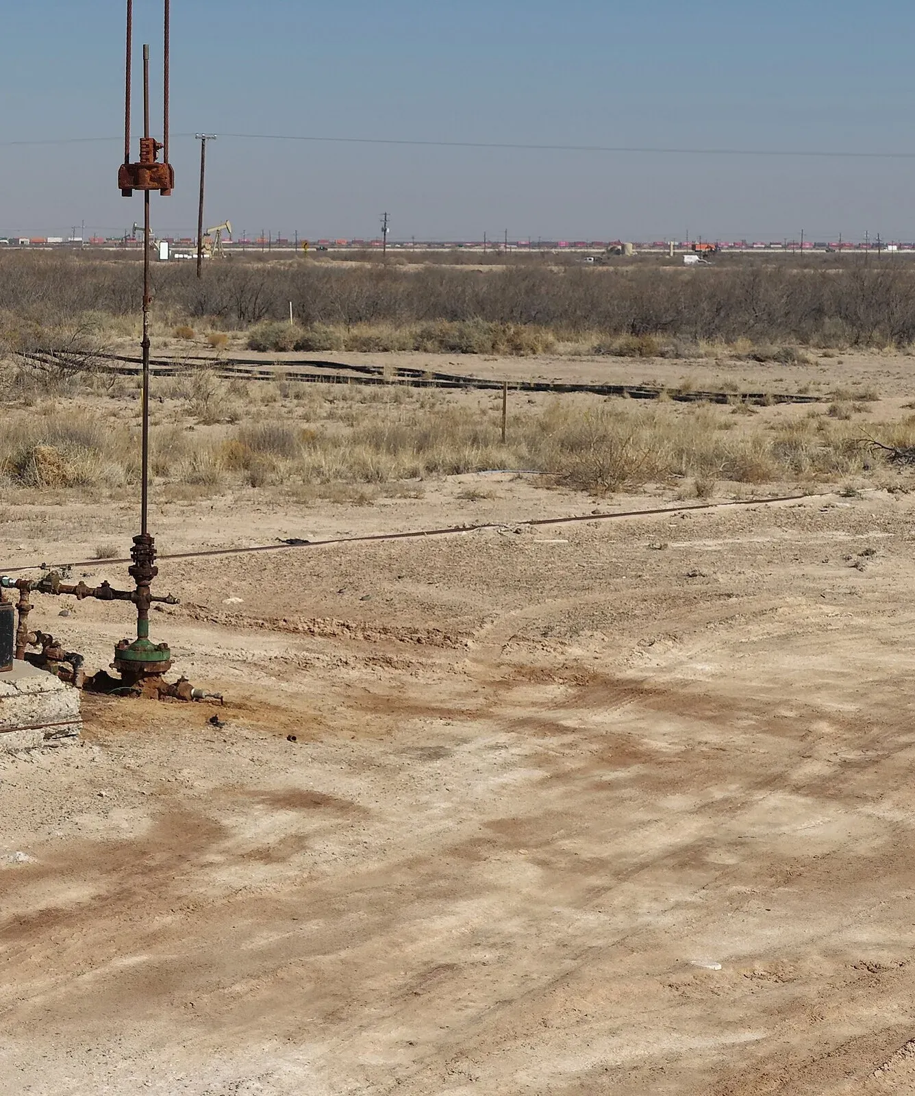 Wellhead and surface flowline on bare caliche at a pumpjack near Monahans, Texas, where a leak would become oil contaminated soil
