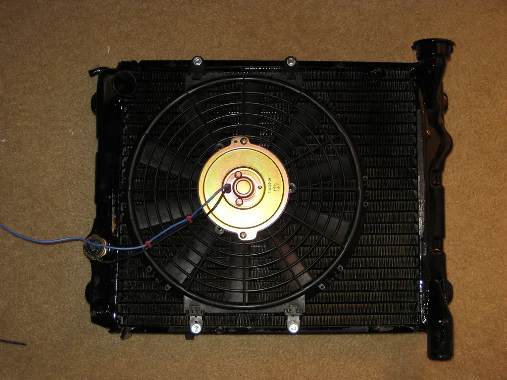 Radiator core with rows of thin fins between the tubes and an electric fan mounted on the back
