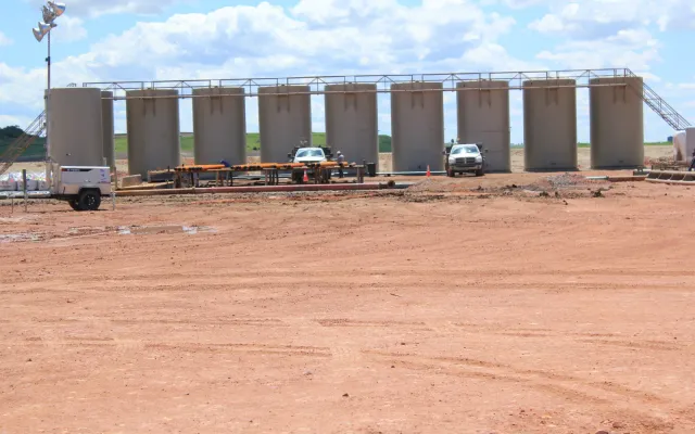 Row of vertical oil field tanks with a catwalk at a tank battery on a new production pad, an example of SPCC plan requirements in practice