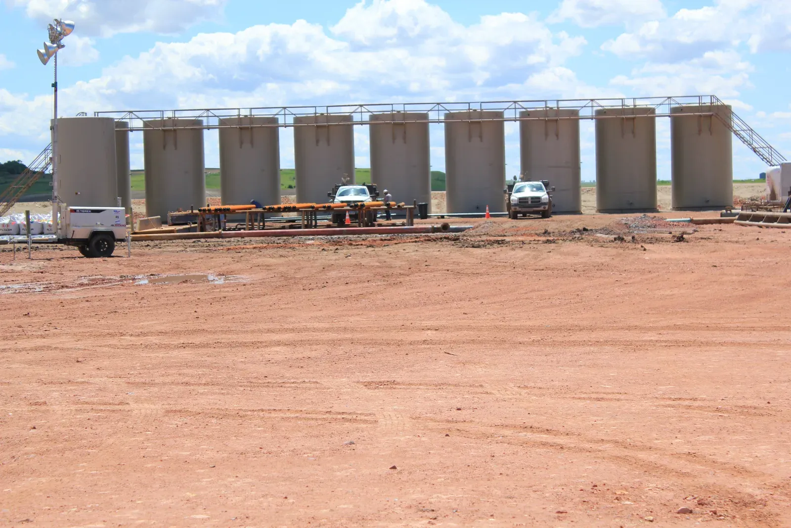 Row of vertical oil field tanks with a catwalk at a tank battery on a new production pad, an example of SPCC plan requirements in practice