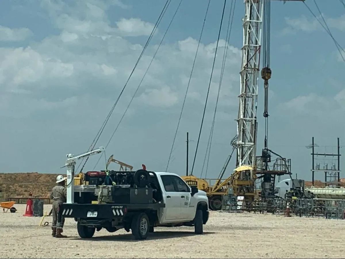 Worker beside an equipment pickup truck on a rig location