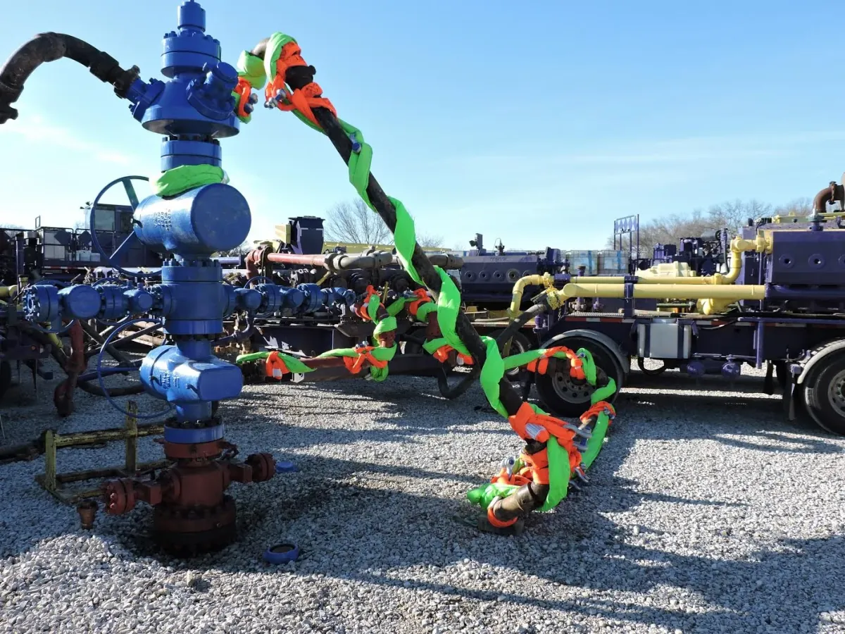 Orange and green hose restraints on a wellhead's fluid lines